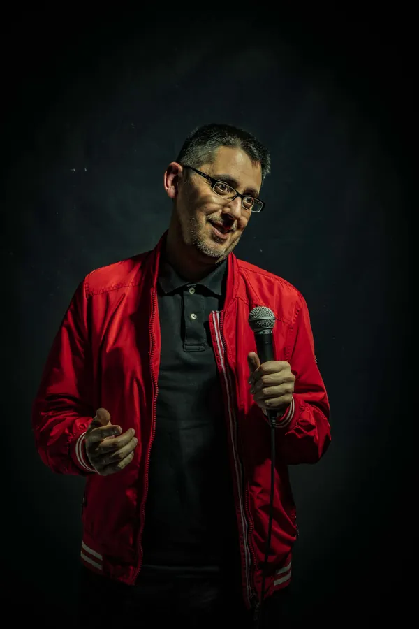 Marcos Félix con chaqueta roja y micrófono, sobre fondo negro.